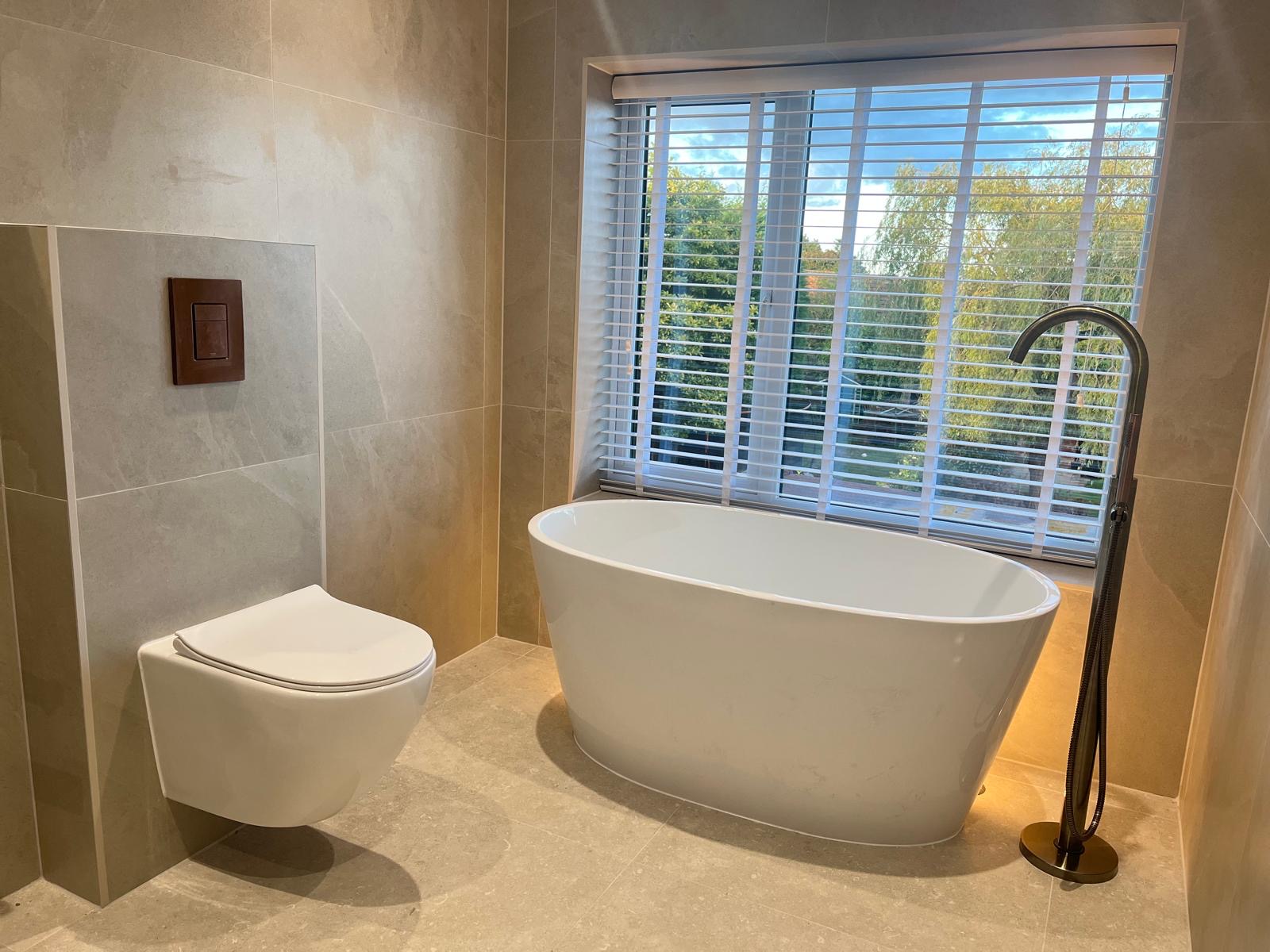 Completed modern bathroom with freestanding bath and wall-hung toilet